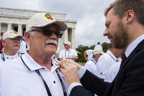 A Vietnam Veteran receives his Vietnam Veteran lapel pin from Vietnam War Commemoration staff.