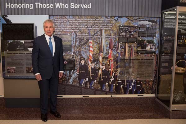 Former Secretary of Defense Chuck Hagel stands next to his quote in a hallway dedicated to veterans.