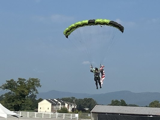 Skydivers deliver the American and POW flags. 