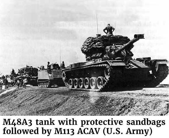 Photo of a M48A3 tank with protective sandbags followed by M113 ACAV (U.S. Army)