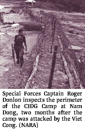 Photo of Special Forces Captain Roger Donlon inspects the perimeter of the CIDG Camp at Nam Dong, two months after the camp was attacked by the Viet Cong. (NARA)